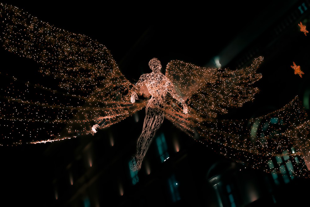 a statue of a man with wings is lit up at night