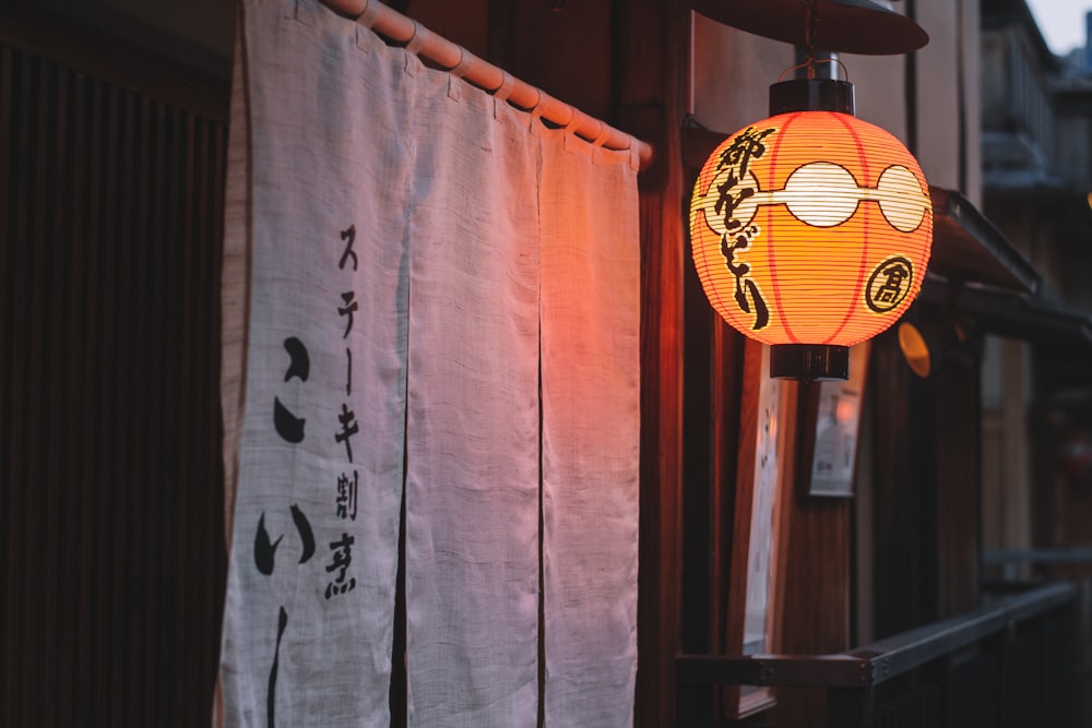 a chinese lantern hanging on the side of a building