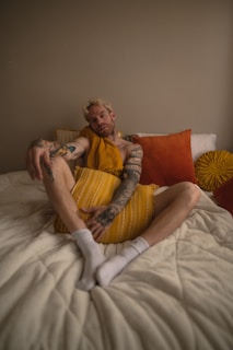 a man with tattoos sitting on a bed