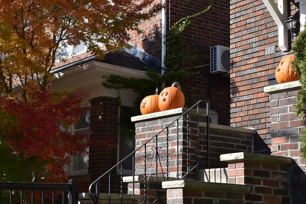 two pumpkins sitting on top of a brick wall