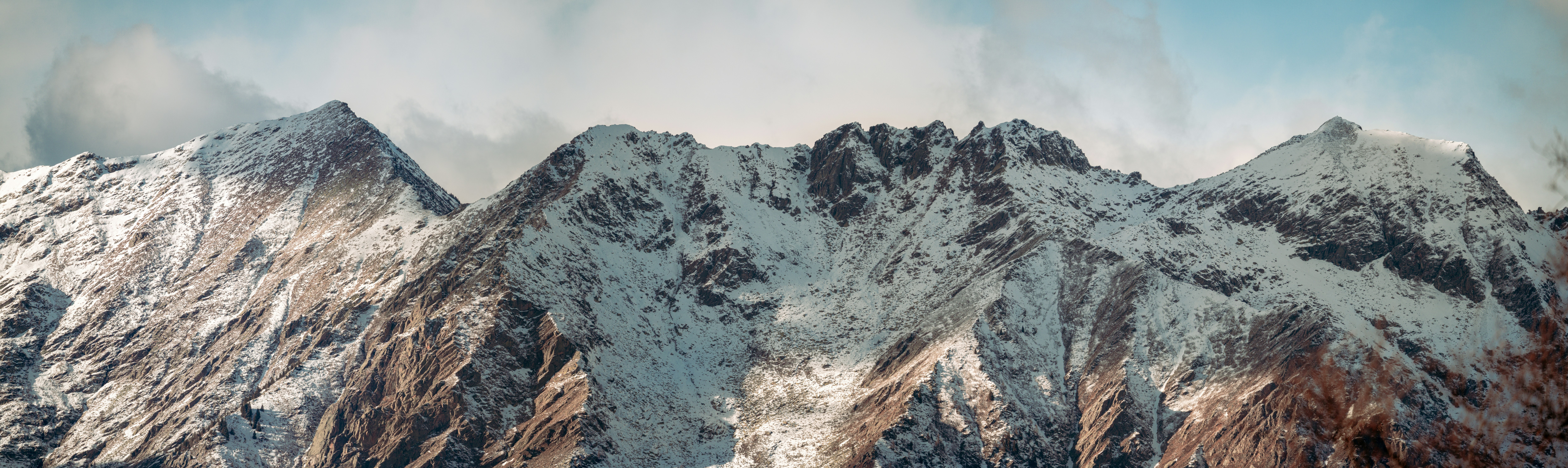a snow covered mountain range under a cloudy sky