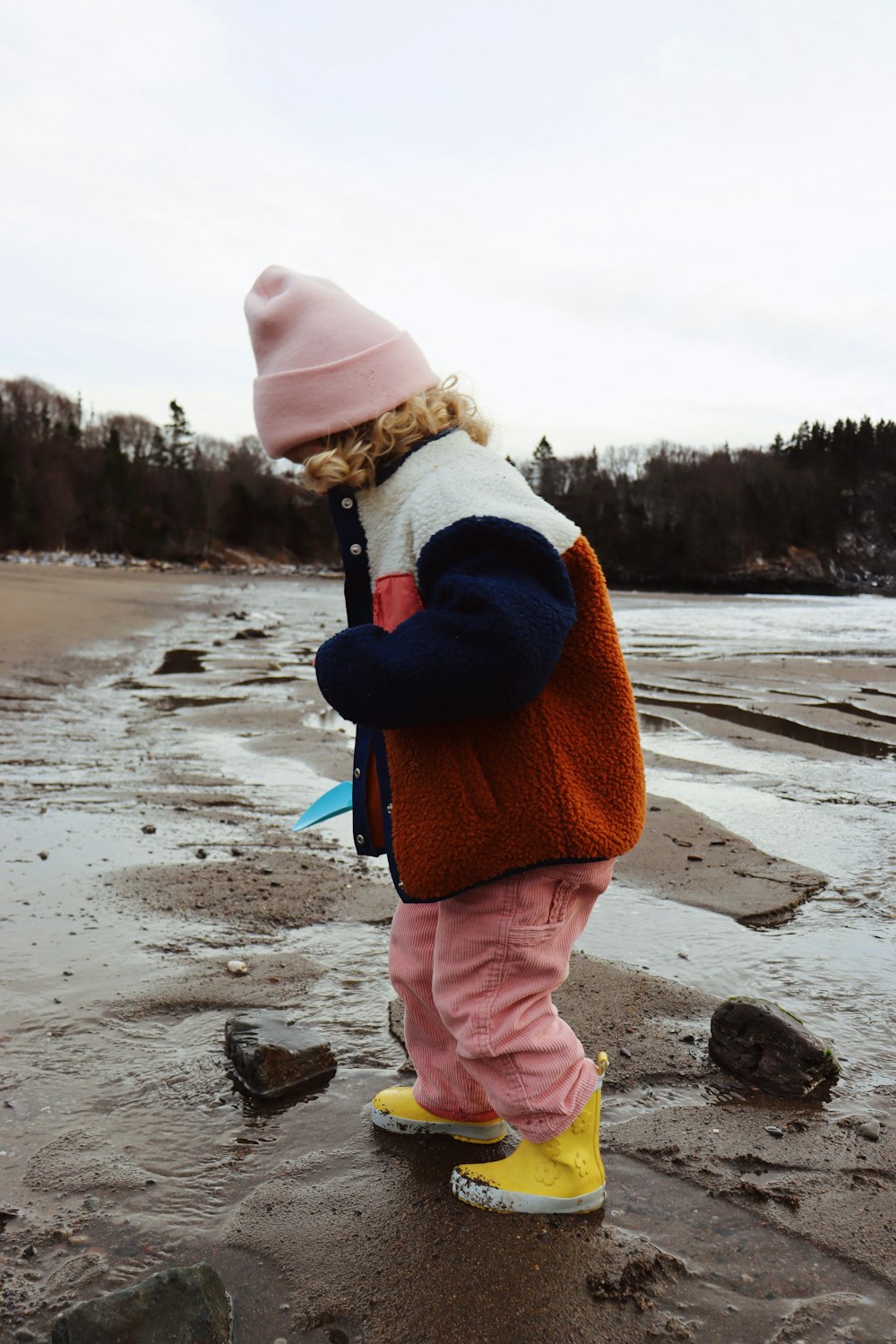 a little girl standing on top of a sandy beach