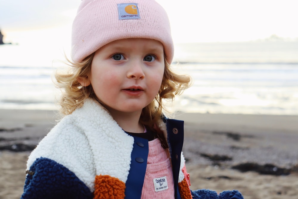a little girl wearing a pink hat and jacket