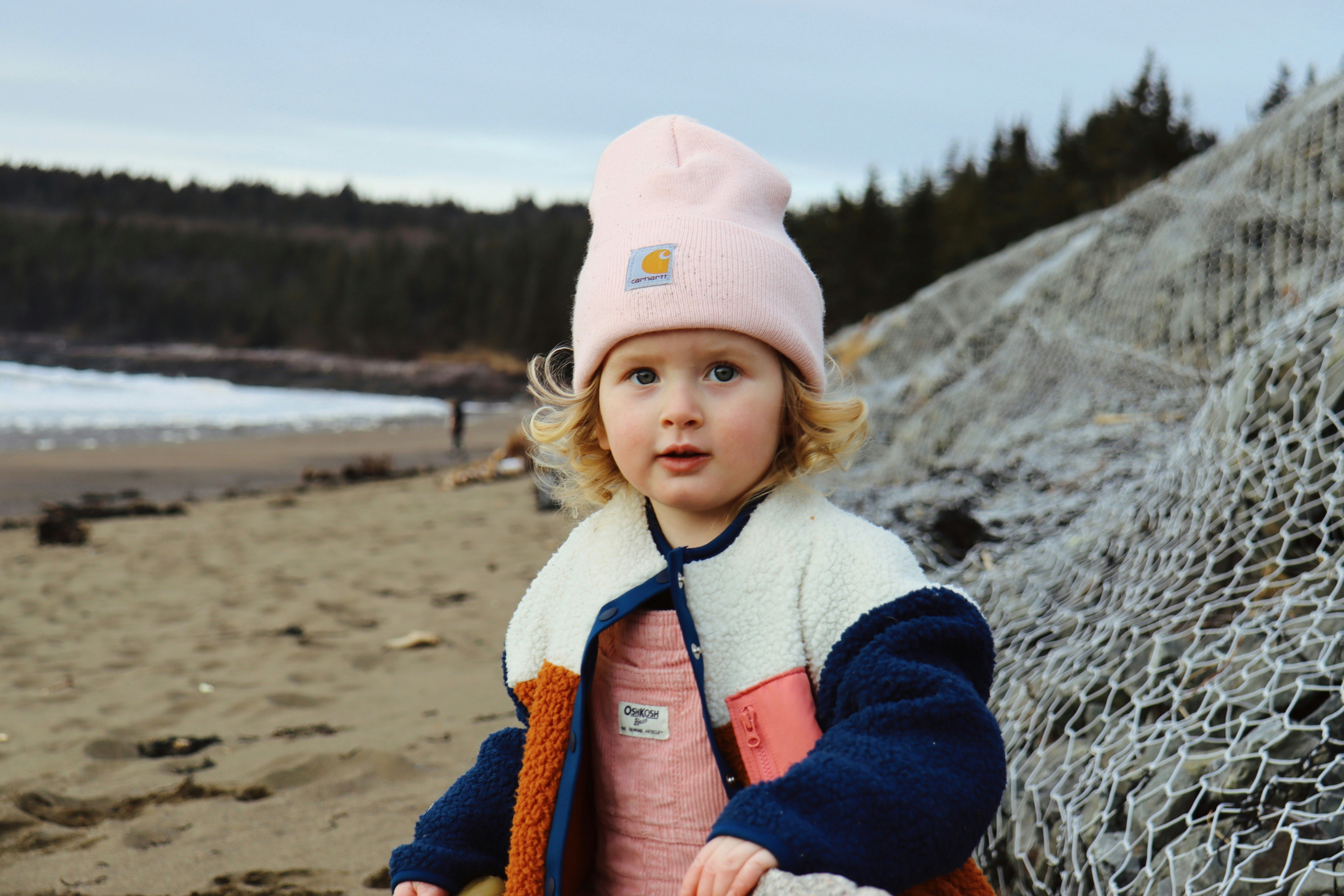a little girl standing on a beach next to a net