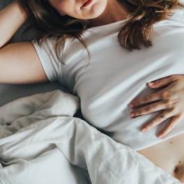 a woman laying in bed with her stomach exposed