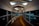 A modern, curved pedestrian walkway with large windows and a wooden floor. The ceiling features geometric patterns with inset lighting, creating a futuristic ambiance. The pathway includes a tactile guide path for the visually impaired.