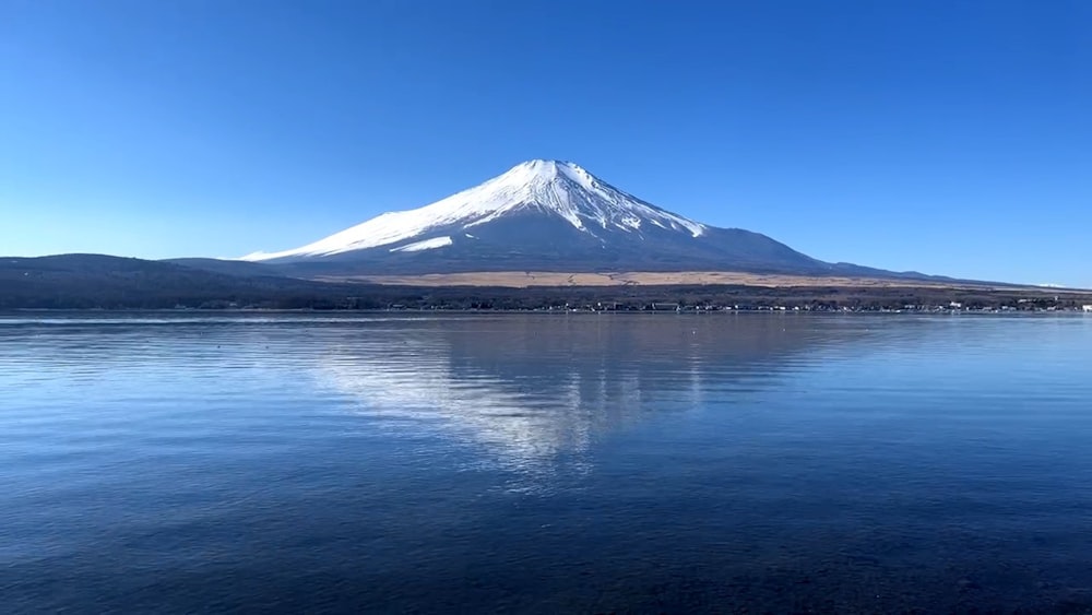 Una montagna innevata seduta sulla cima di un lago