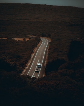 a truck driving down a road in the middle of a field