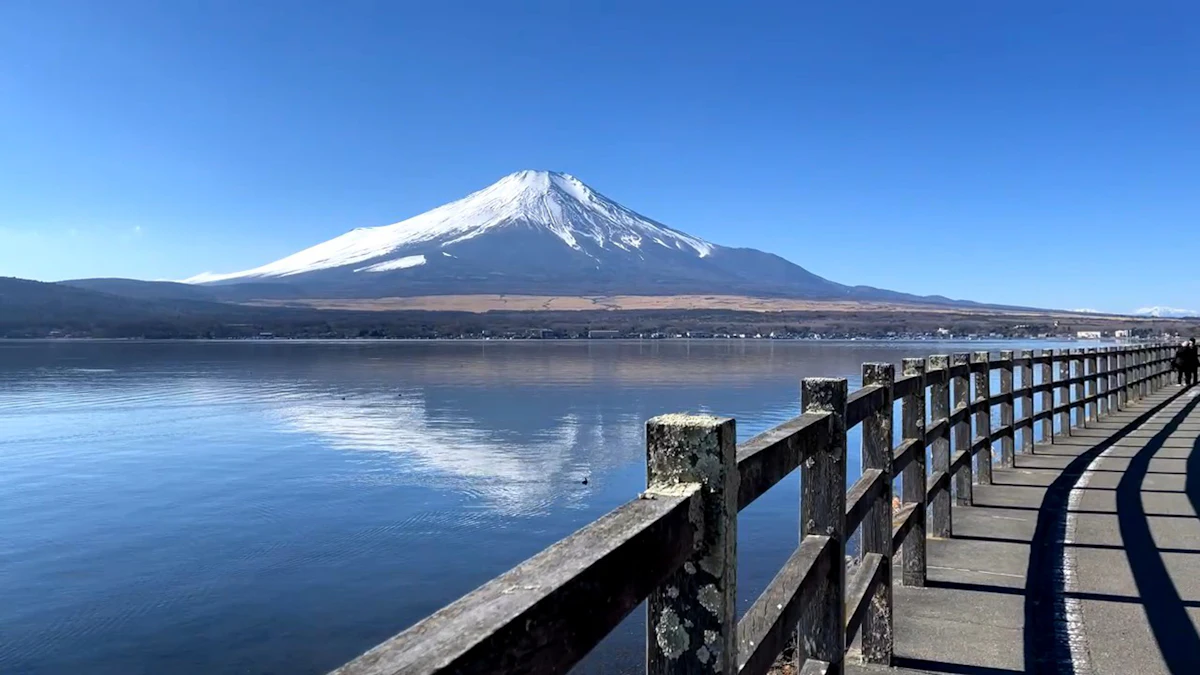 Snow-capped Mount Fuji across Lake Yamanaka, with a lakeside boardwalk on the right