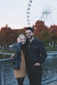 a man and a woman posing for a picture in front of a ferris wheel