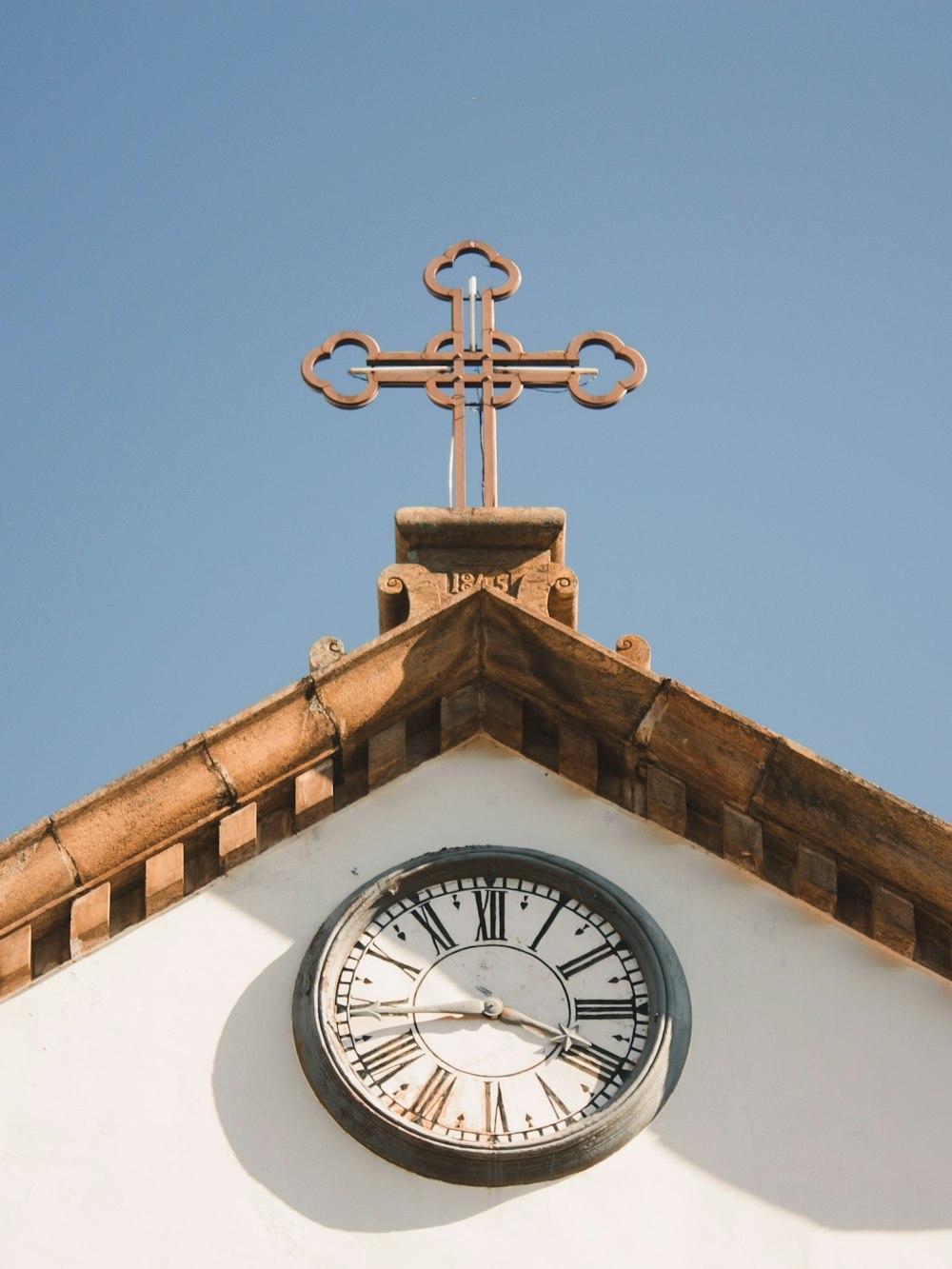 a clock on the side of a building with a cross on top