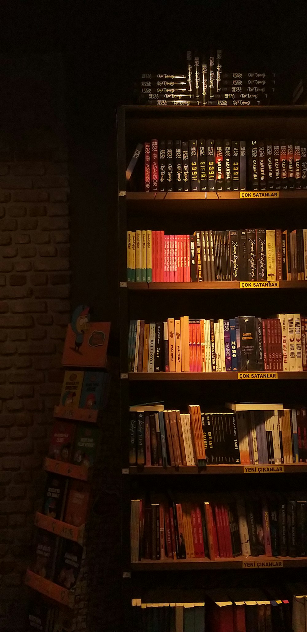 a bookshelf filled with lots of books next to a brick wall