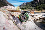 Close-up of fishing gear laid out on a wooden dock by a mountain lake.
