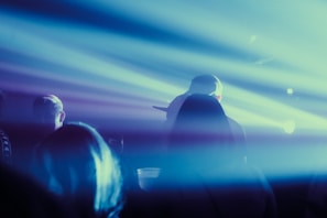 Group shot of the main cast members standing against a dark, textured backdrop with subtle purple and red hues