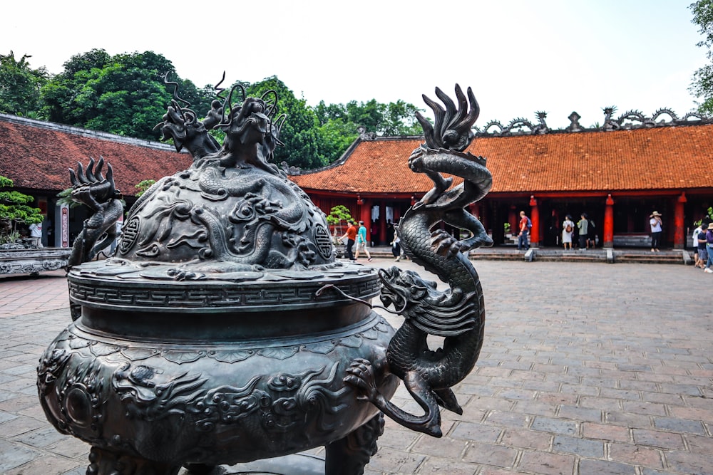 a large metal vase sitting on top of a brick floor