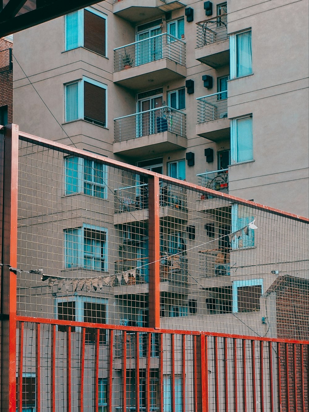 a tall building with balconies behind a fence