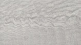 Fine, textured sand with subtle ripples creating a soothing pattern across the surface.