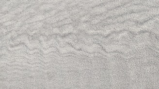 Fine, textured sand with subtle ripples creating a soothing pattern across the surface.