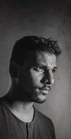 Monochrome portrait of the grey man with a contemplative expression in a narrow alley.