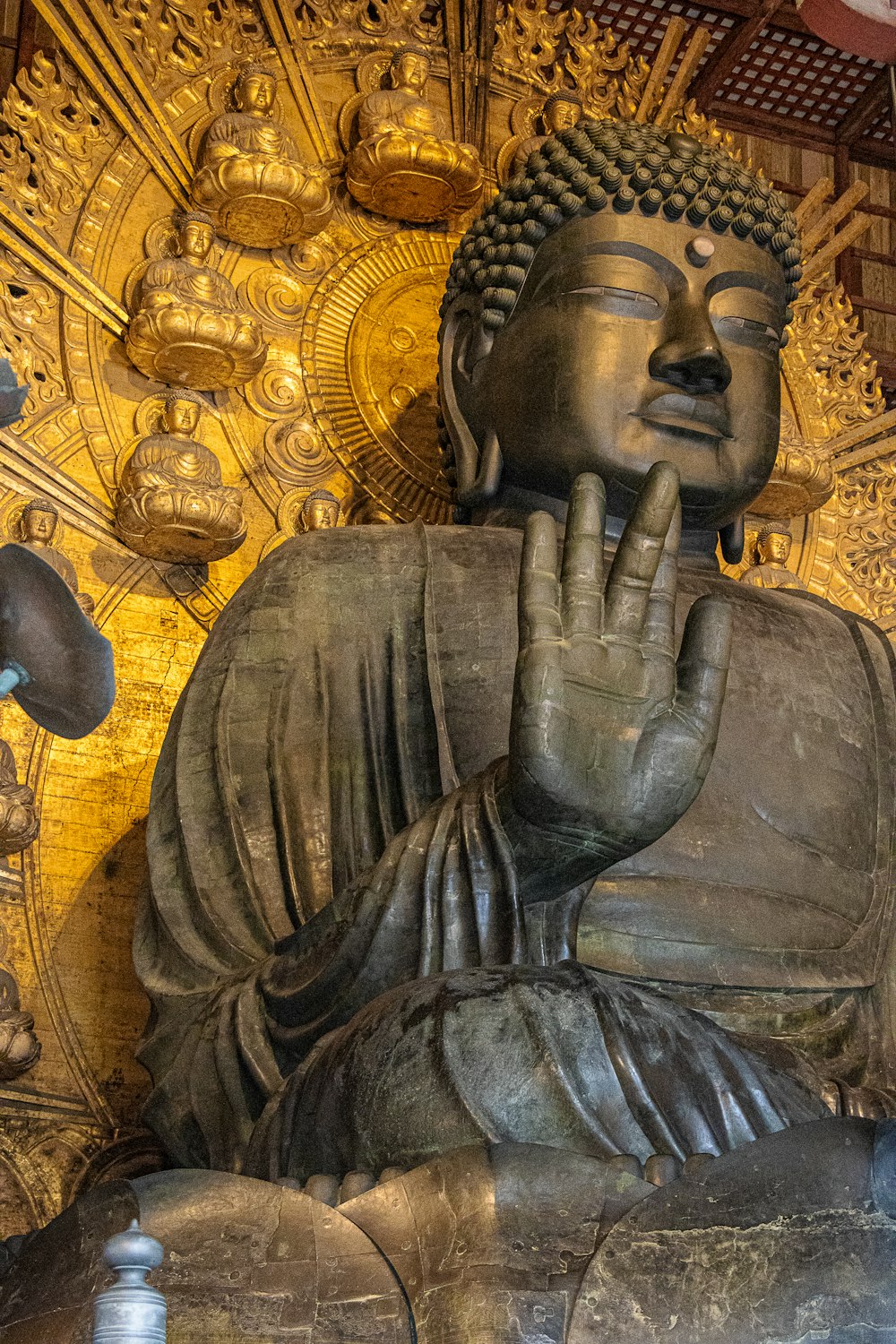 a large buddha statue sitting in front of a golden wall