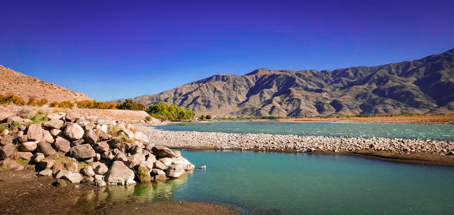 A serene landscape showing clear water flowing over smooth stones with geological layers visible beneath.