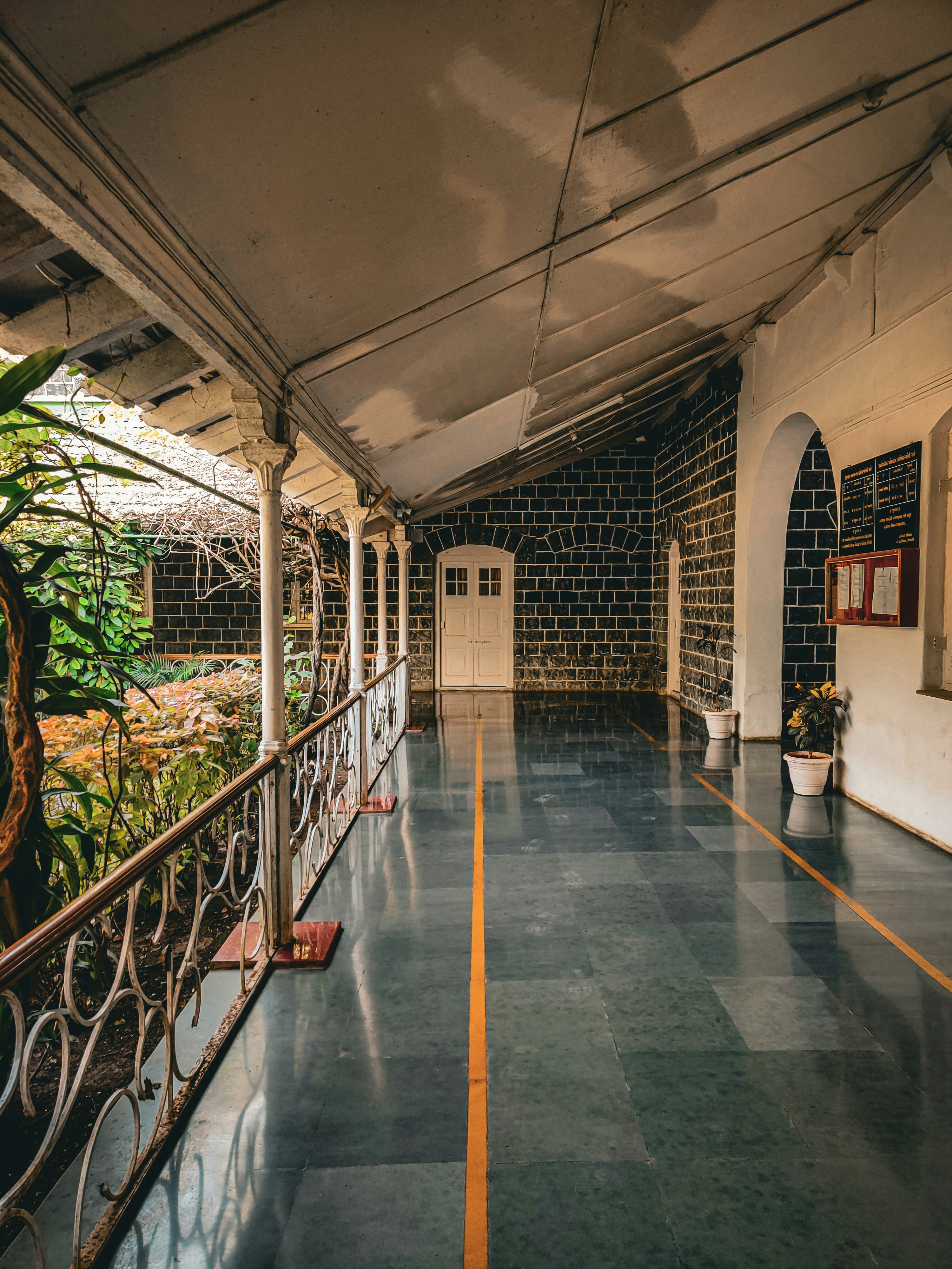 a long hallway with a metal railing and potted plants