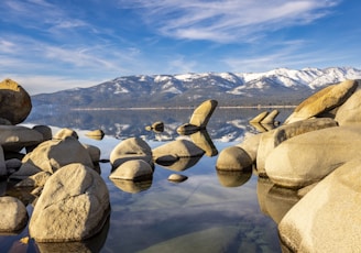 a lake with rocks and mountains in the background