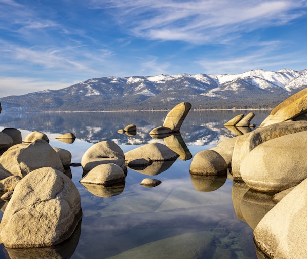 a lake with rocks and mountains in the background