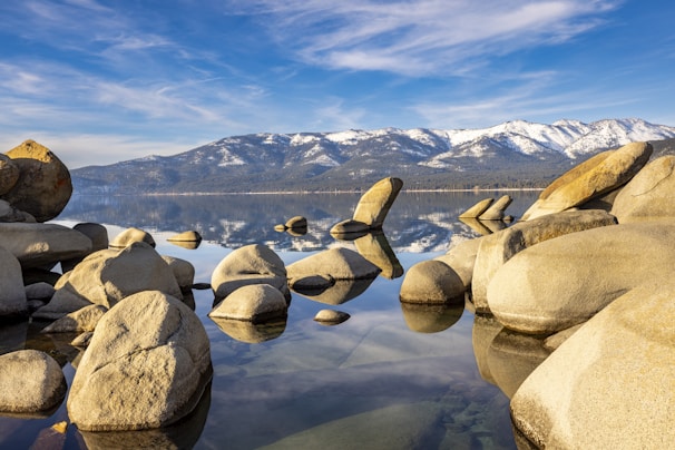 a lake with rocks and mountains in the background