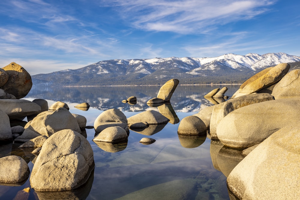 a lake with rocks and mountains in the background