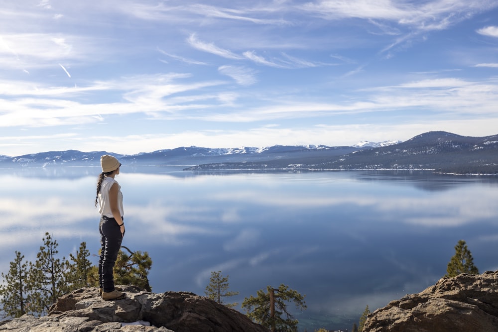 Una donna in piedi sulla cima di una montagna che domina un lago