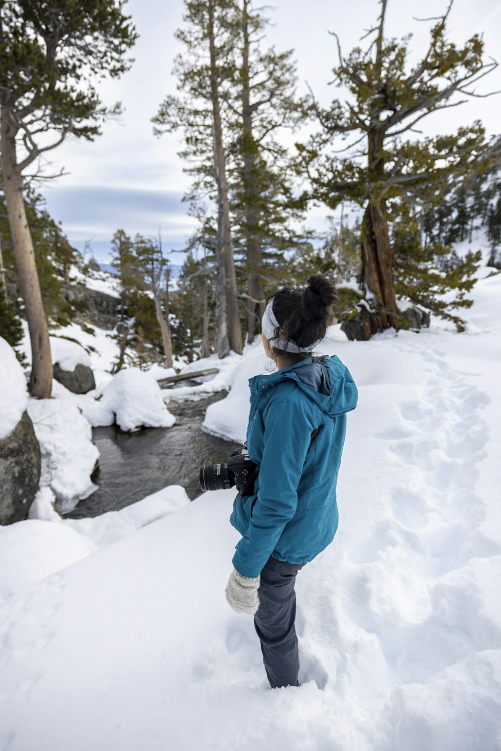 a person standing in the snow looking at a stream