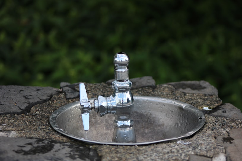 Close-up of a shiny PTMT tap installed on a kitchen sink, highlighting its smooth finish.