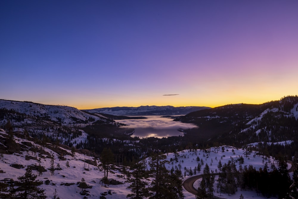 the sun is setting over a snowy mountain