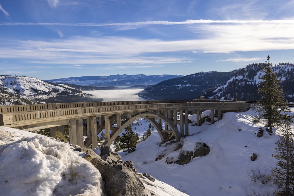 a bridge over a snow covered mountain with mountains in the background