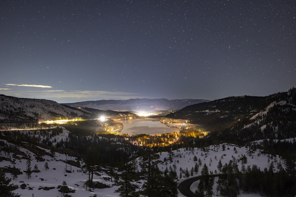 a night view of a snowy mountain with a lake
