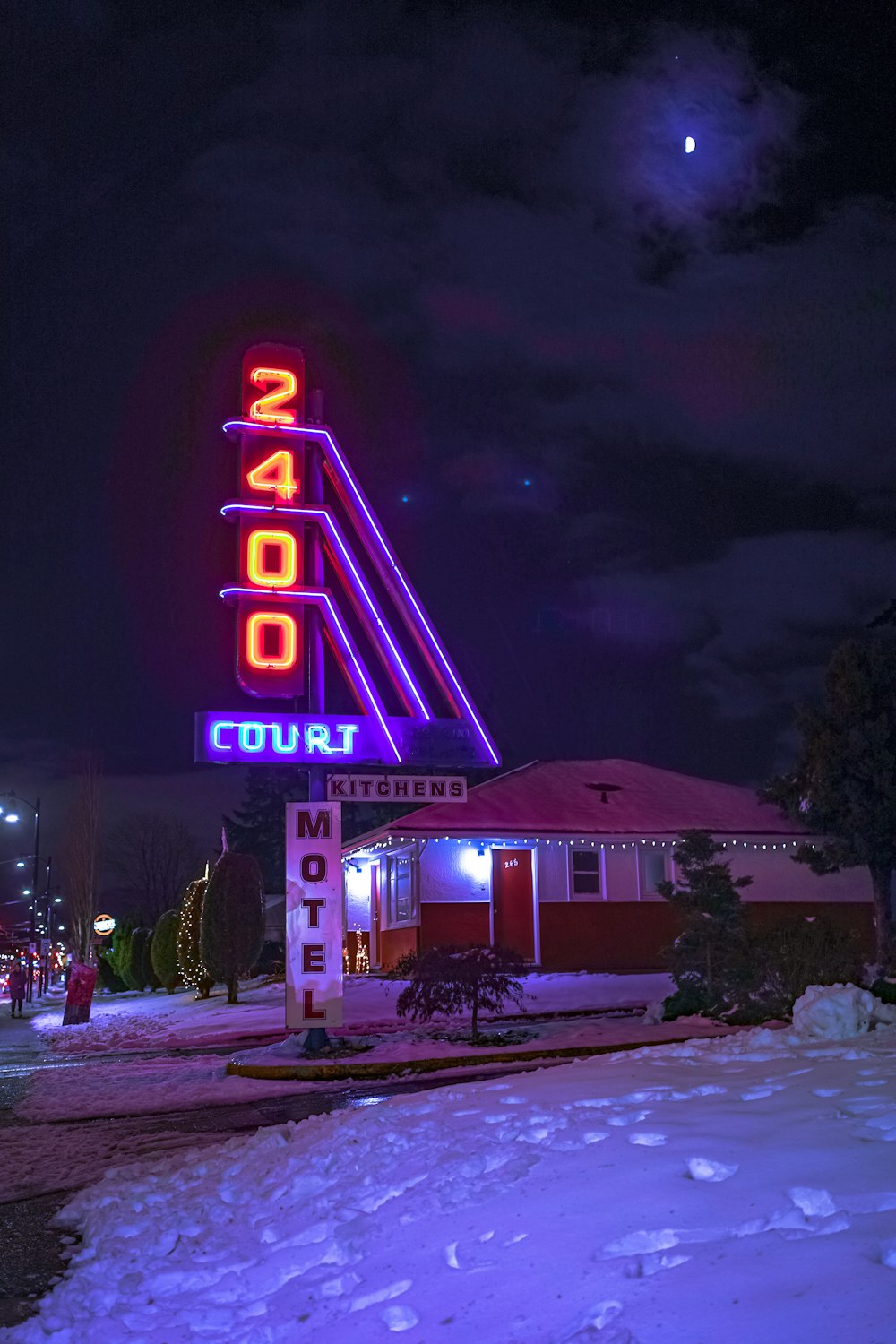 a motel sign lit up at night in the snow