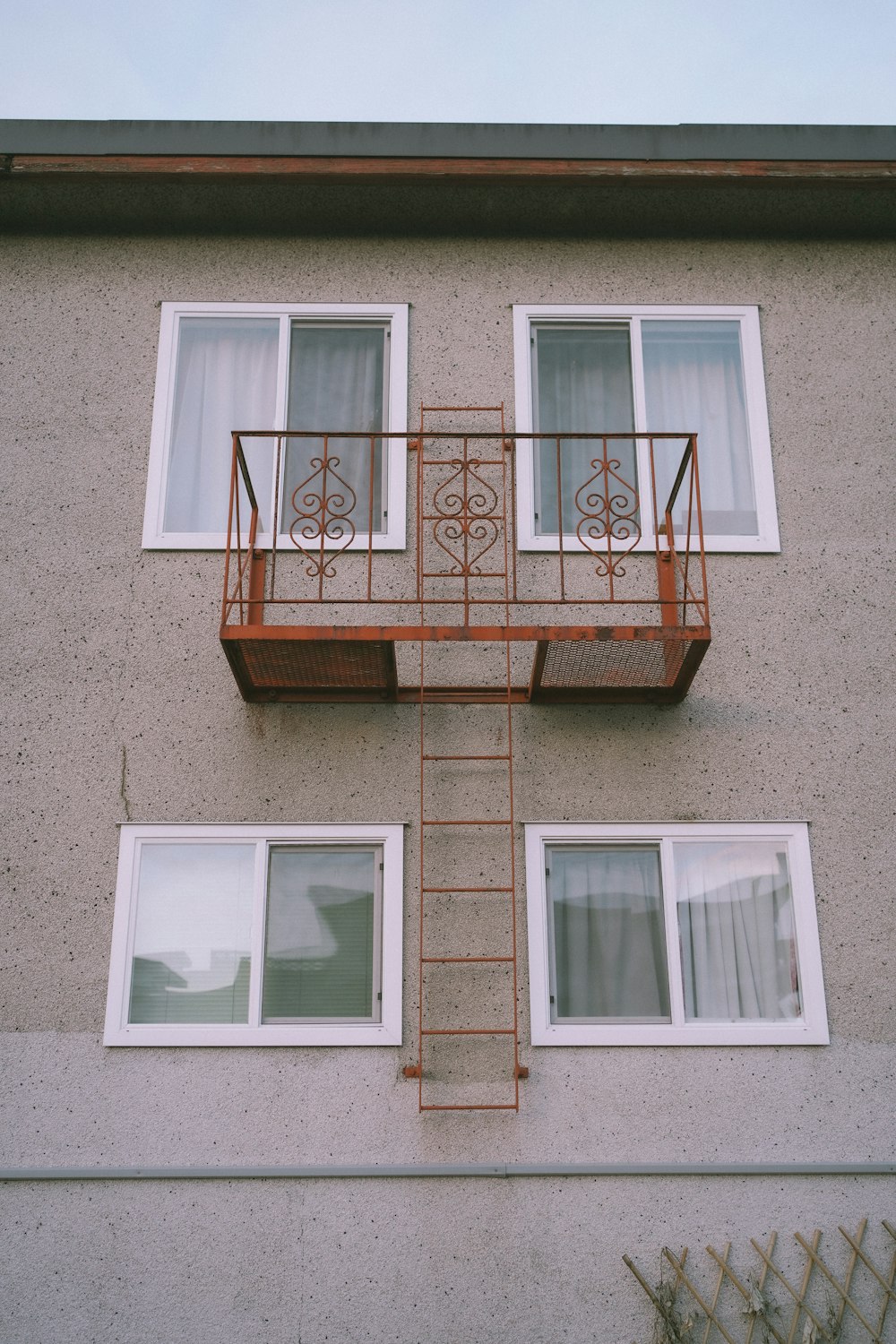 a building with two windows and a red ladder