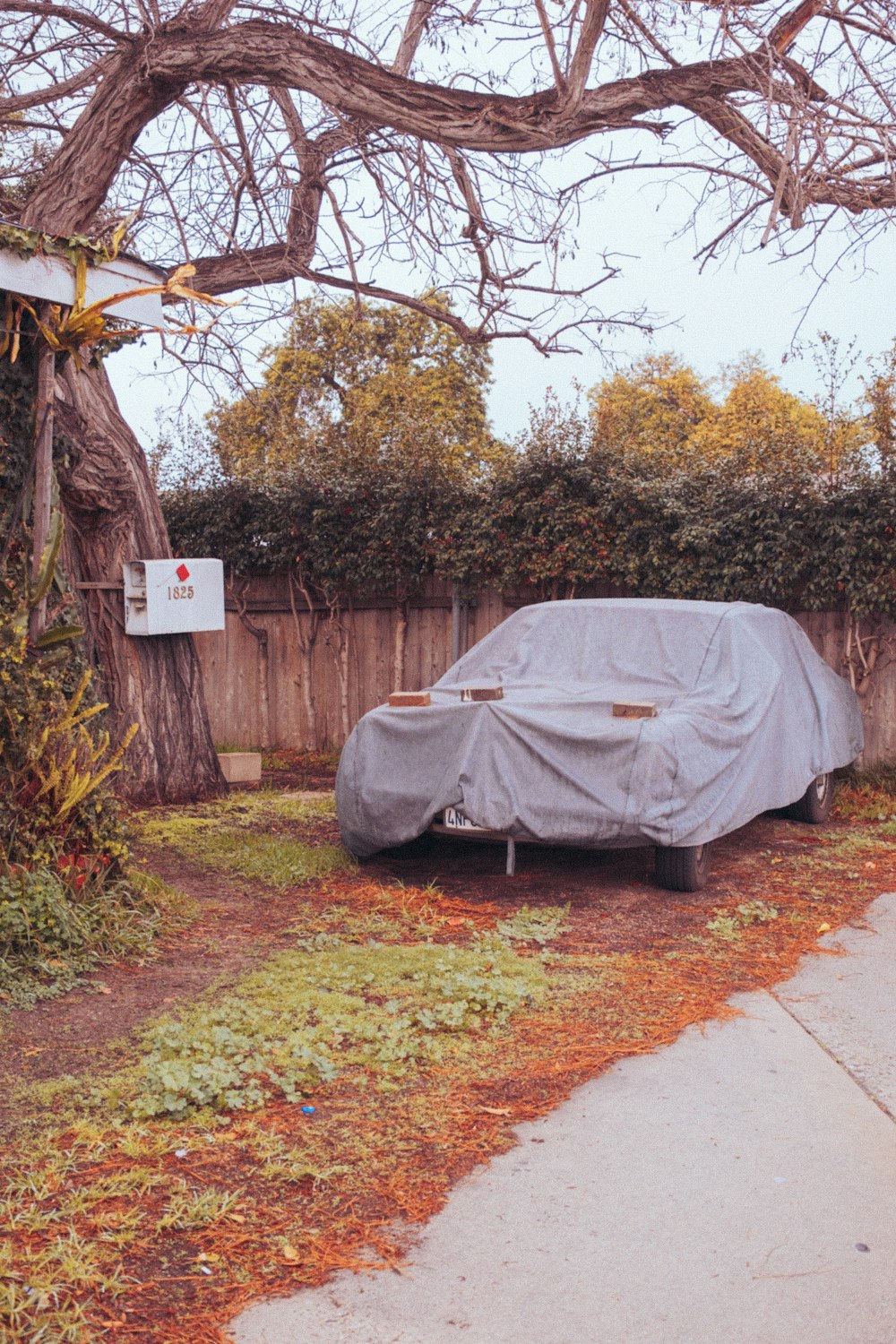 a car covered in a tarp parked on the side of a road