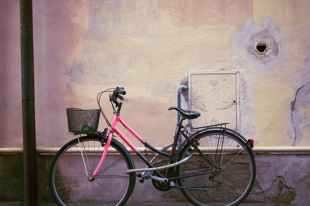 a pink bicycle parked next to a wall