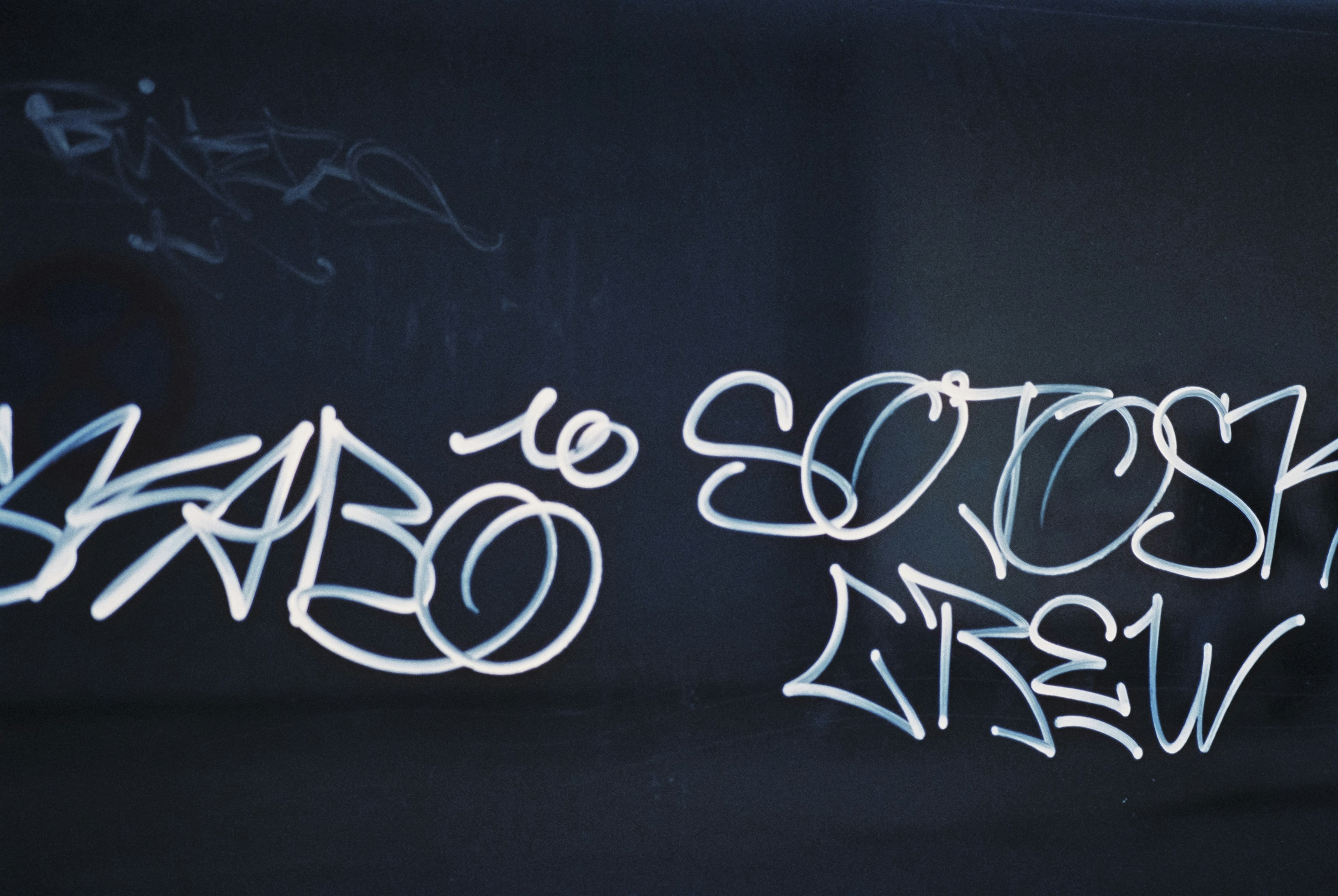 a black wall with graffiti written on it