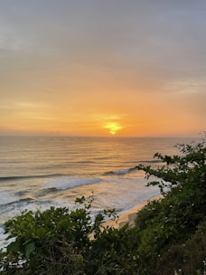 A serene Hawaiian landscape at sunset, with gentle waves and lush greenery.