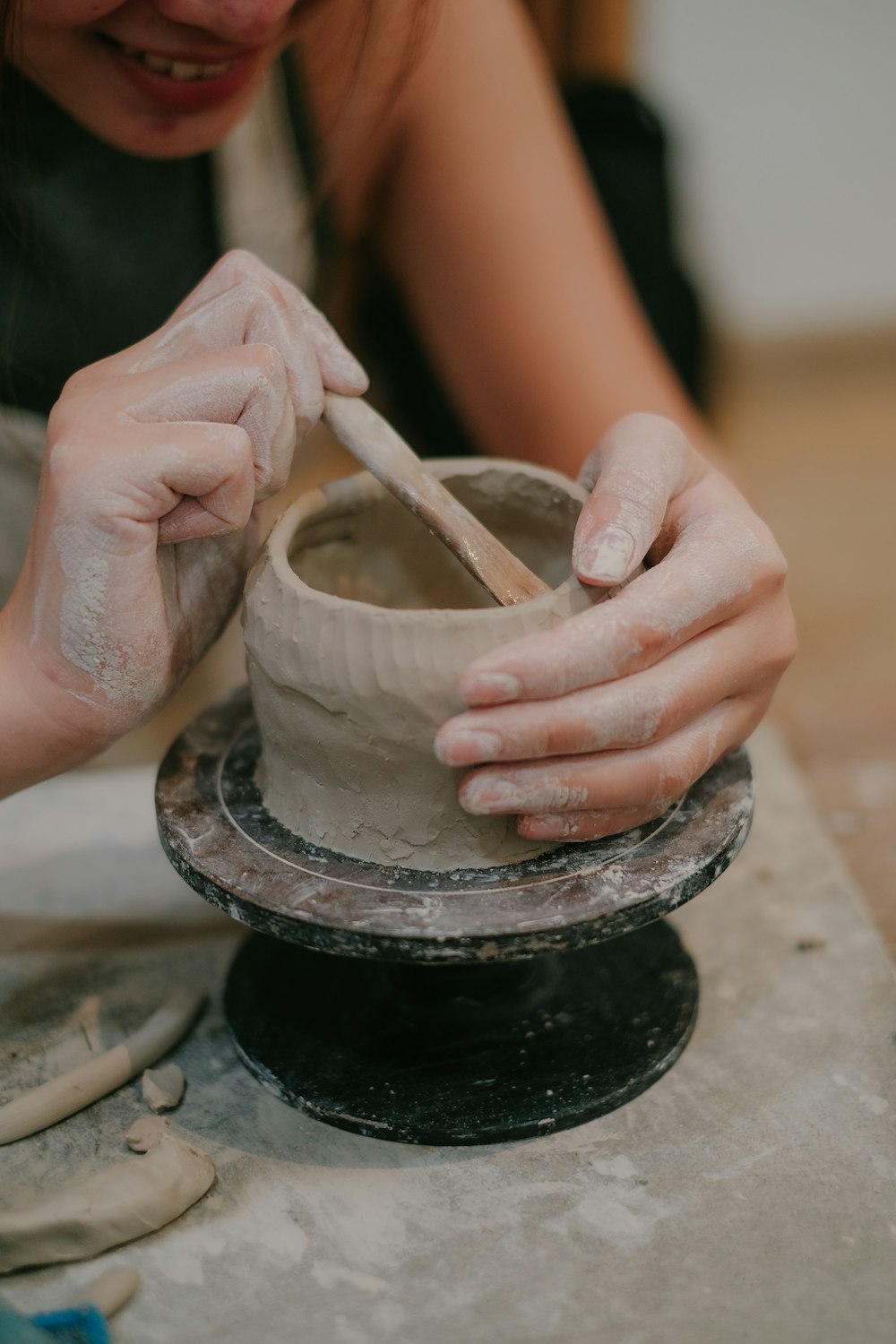 a woman is making a vase out of clay