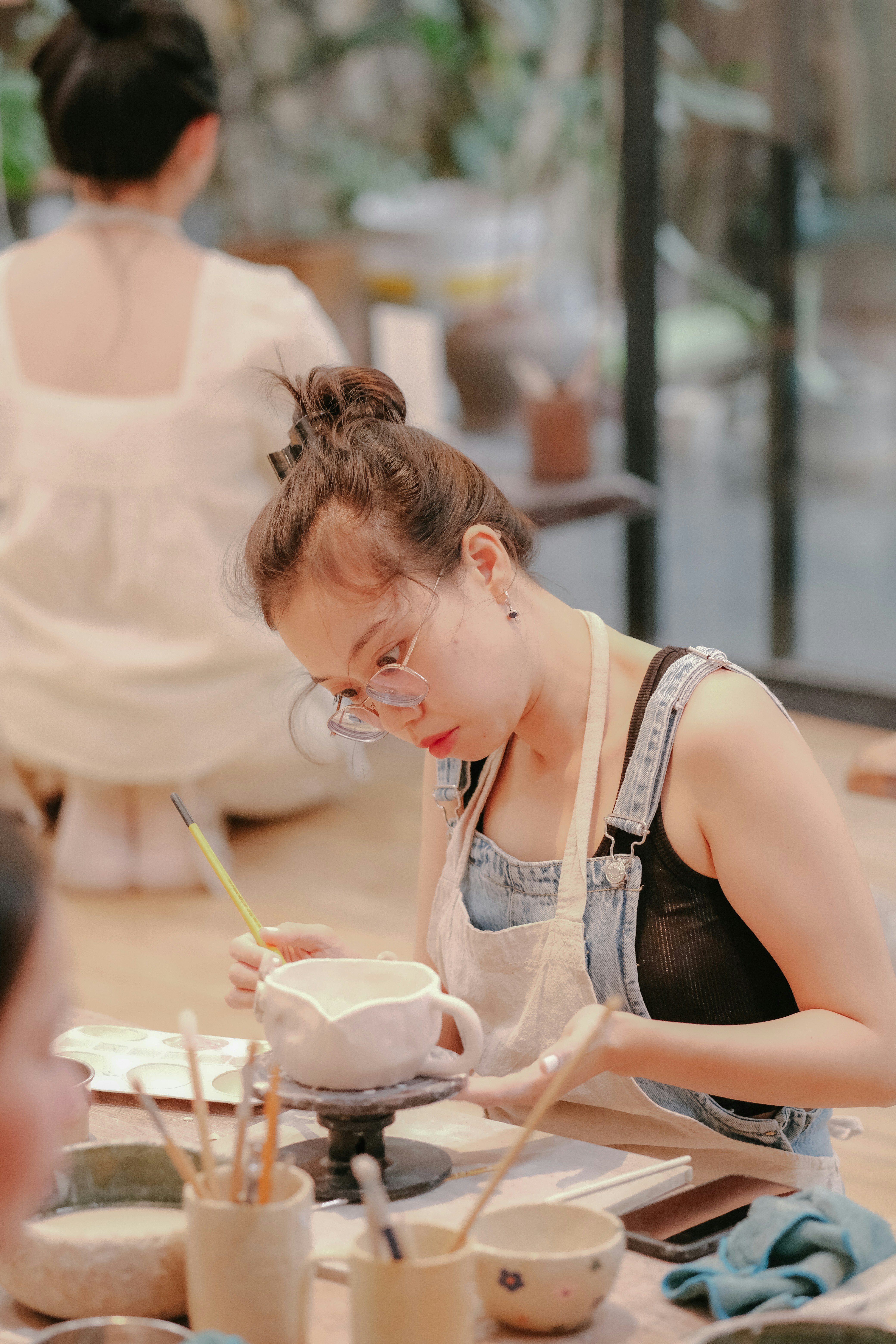 a woman in an apron painting a bowl on a table
