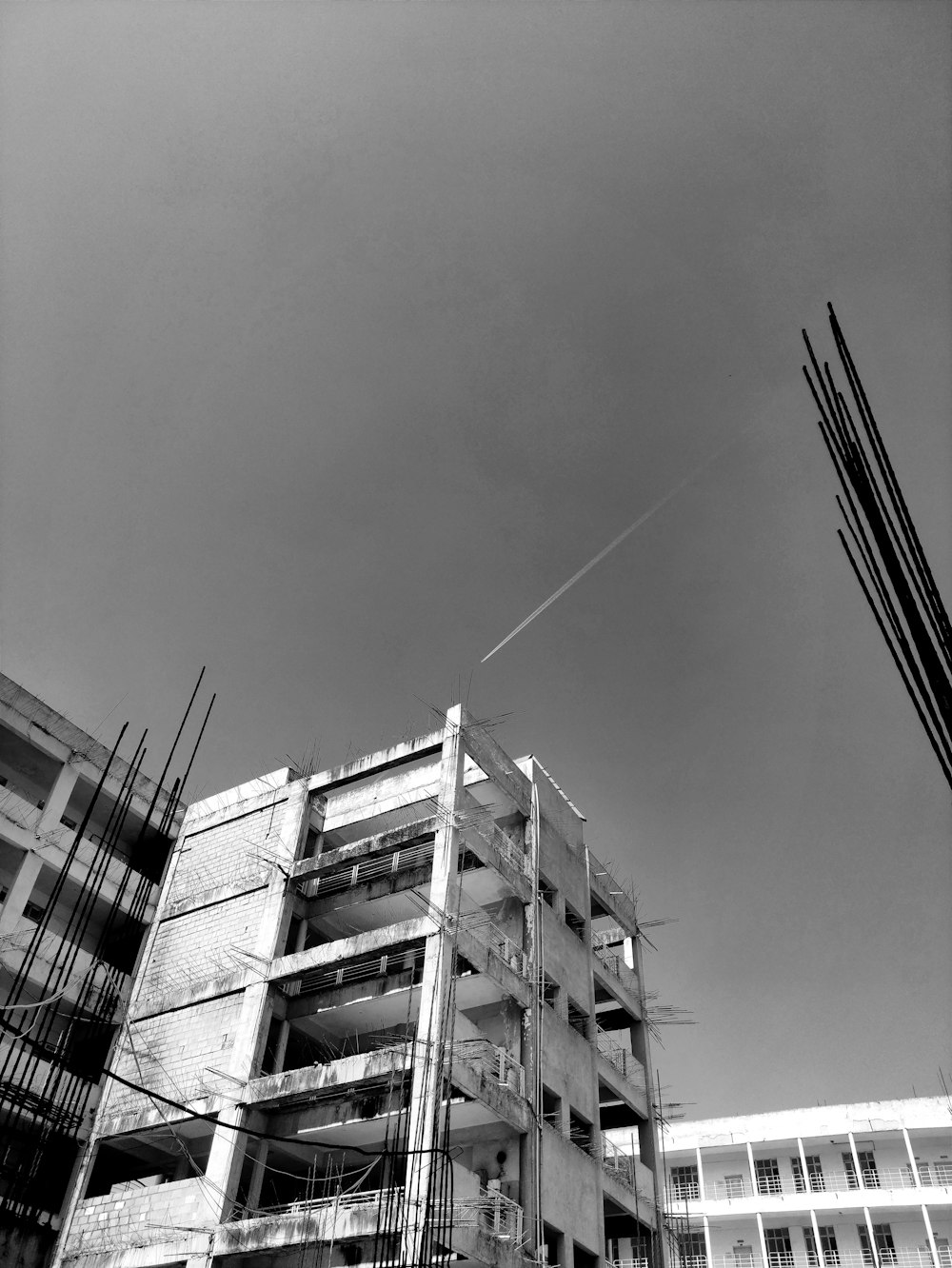 a black and white photo of a building with a plane in the sky