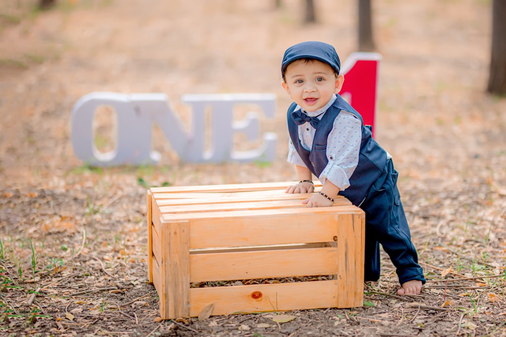 a little boy sitting on top of a wooden box