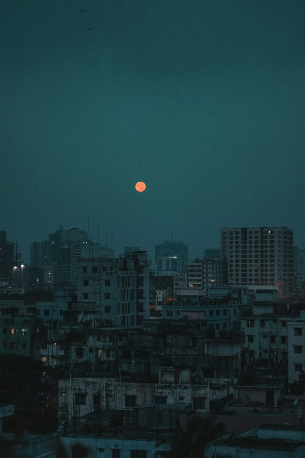 a full moon is seen over a city at night