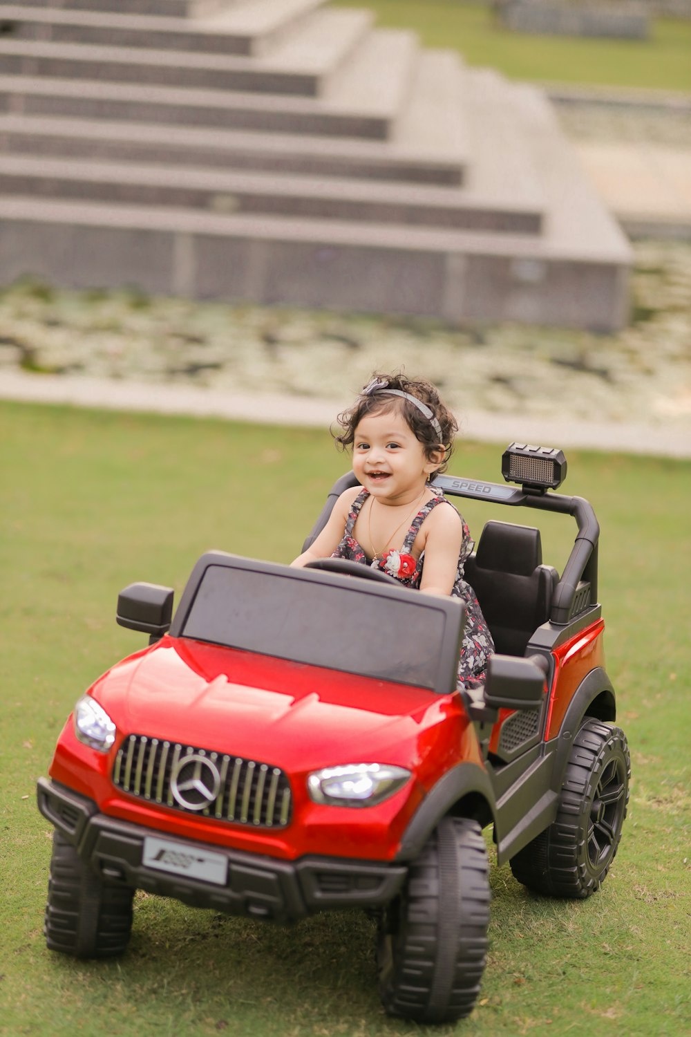 a little girl riding a red toy car