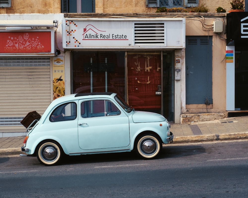 a small blue car parked in front of a building