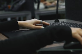 Close-up of hands typing on a laptop keyboard in an office